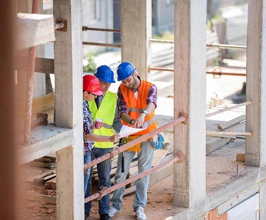 Three construction workers are standing in a building.