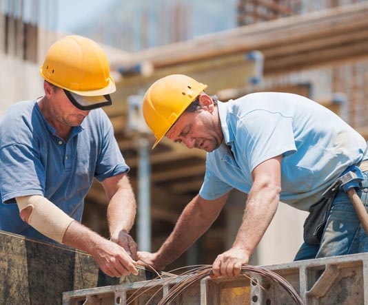 Two men in hard hats working on a building.