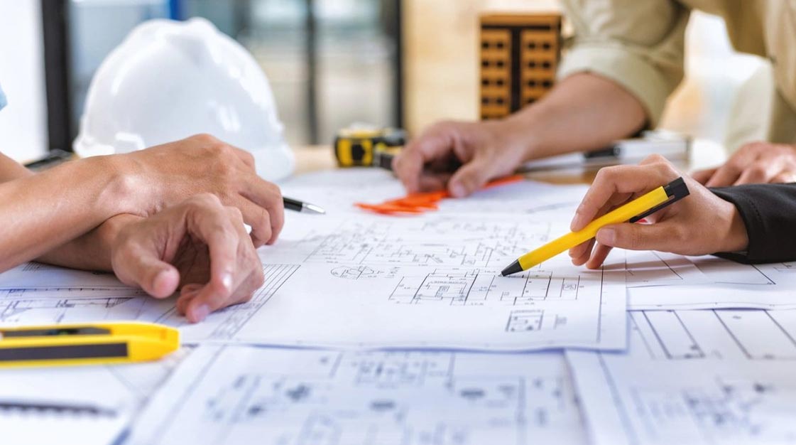 A group of people sitting at a table with papers and pencils.